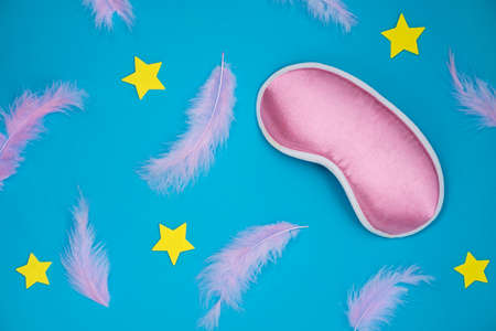 Scattered pink feathers. Paper background with the feathers, stars and sleeping maskの写真素材
