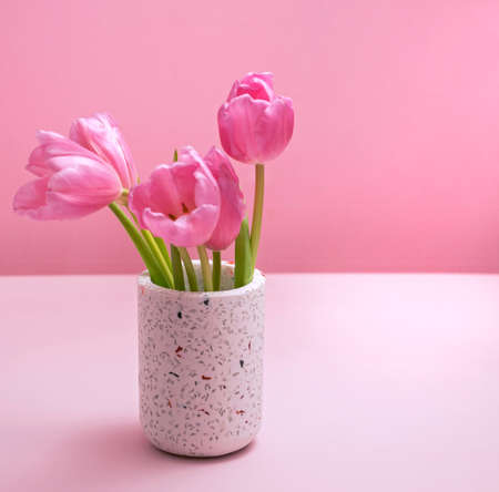 gentle spring background in pink with vase and tulipsの写真素材