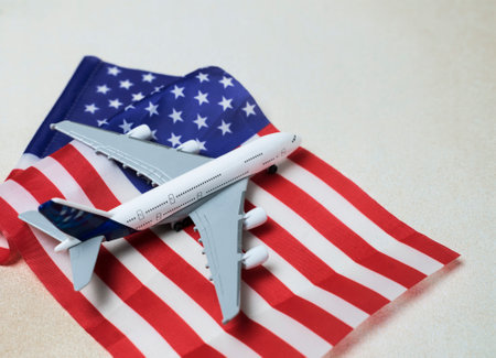Miniature white airplane on usa flag. Creative concept of air transportation, tourism, travel. Copy space for textの写真素材