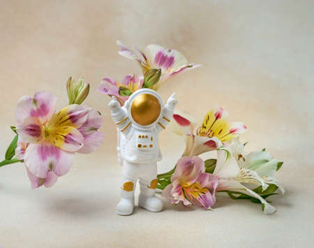 Happy astronaut standing with raised hands surrounded by flowersの写真素材