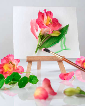 bright summer flower on the artist's easel and a brush with paint, summer vibes backgroundの写真素材