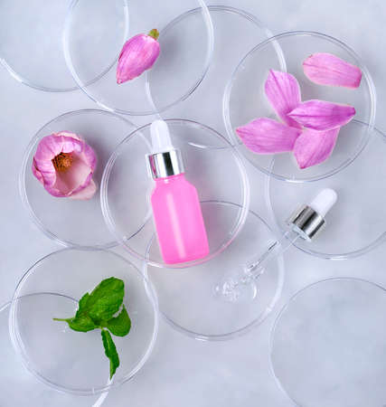 Cosmetic skincare background. Herbal medicine with magnolia flowers. Petri dishes, cosmetics tubes. Natural skincare backgroundの写真素材