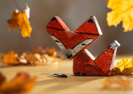 wooden fox toy made from driftwood. Autumn composition with handicraft from a tree found on the coast and yellow leavesの写真素材