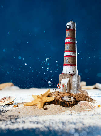 wooden lighthouse made of driftwood.  marine composition with sand, shells and wave splashesの写真素材