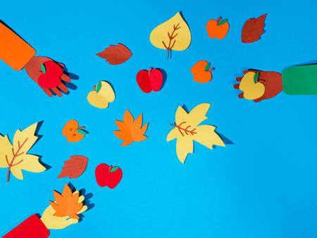 paper craft autumn background, friends hands holding autumn leavs and apples, friendly partyの写真素材