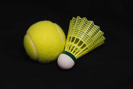 Yellow tennis ball and badminton shuttlecock isolated on blackの写真素材