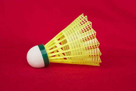 One yellow shuttlecock isolated on redの写真素材