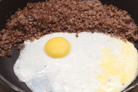 Cooked eggs with buckwheat on fruing pan closeup