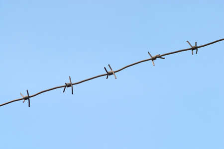 Gray barbed wire isolated on blue