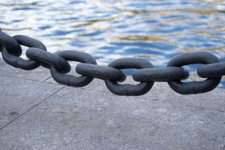 Black chain links closeup before sea embankmentの写真素材
