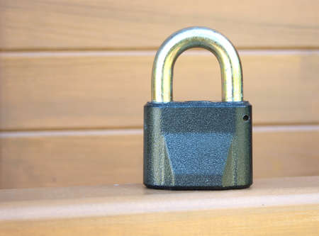 Heavy metal lock before brown wooden wall closeupの写真素材