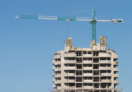 Big hoisting tower crane and top of construction building over cloudless skyのeditorial素材