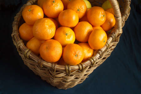 Many ripe oranges crop in brown wicker basket closeupの写真素材