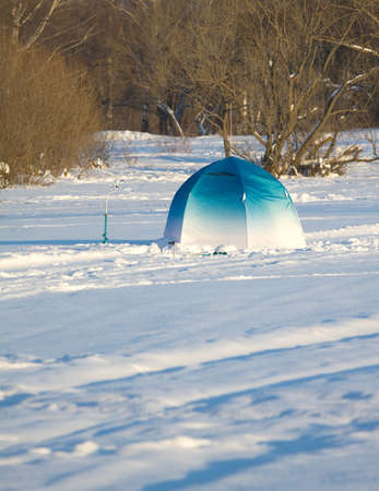 Fisherman color tent on frozen river with snow vertical view