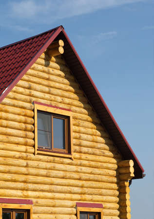 Top of country wooden house with red roof and windows closeupのeditorial素材