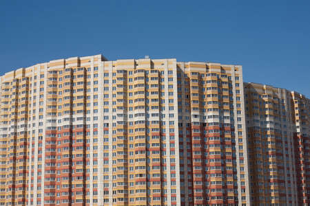 Top section of multi-storey building constructed from bricks over clear blue skyの写真素材
