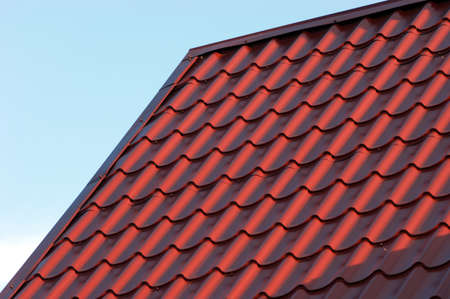 Part of red house roof from metal tile over blue closeupの写真素材