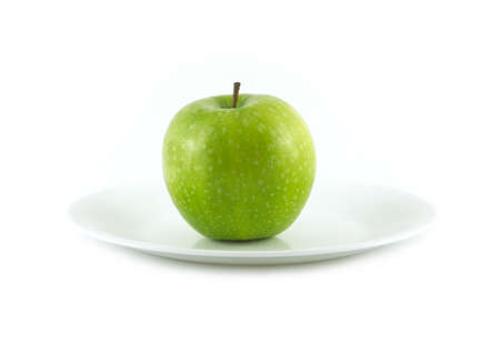 Ripe green ripe apple lays on plate isolated on whiteの写真素材