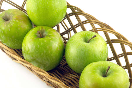Ripe green apples in long brown wicker basket isolated on white closeupの写真素材