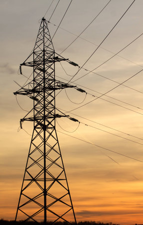 High-voltage power supply line metal tower on beautiful sunset vertical view