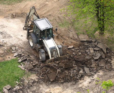 Road construction machinery bucket collects old asphalt