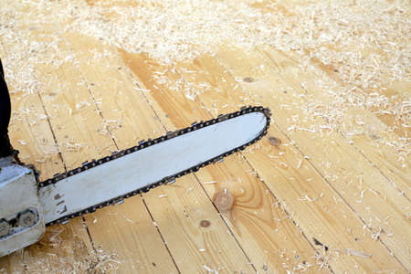 Chainsaw for cutting wood or other materials with a long, thin serrated steel blade close up before sawdust and shavingsの写真素材