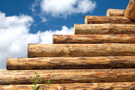 Construction of rural house from logs on a background of blue sky with cloudsの写真素材