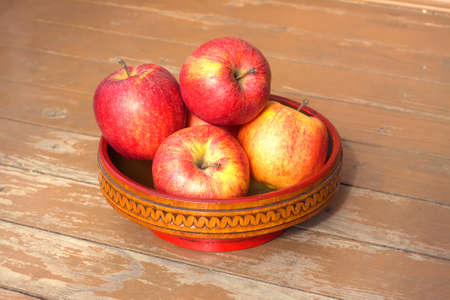Still life with ripe red and yellow apples in wooden bowl on timber background closeupの写真素材