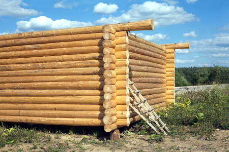 Construction of rural house from heavy logs on a background of blue sky with clouds. Horizontal photoの写真素材