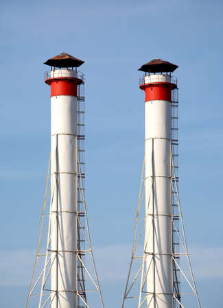 Two white high industrial smoke pipes over clear blue sky vertical view close upの写真素材