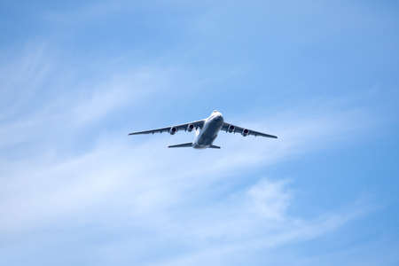 Large four engine jet transport aircraft flying high in the clear blue sky with white cloudsの写真素材