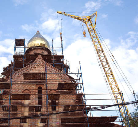 Big yellow tower crane on russian red brick church construction processの写真素材
