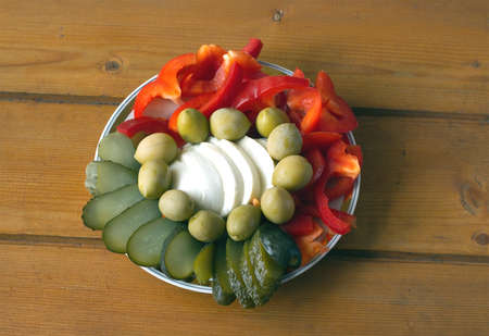 Still life with sliced fresh and pickled vegetables on the plate on a wooden surface. Top view closeupの写真素材