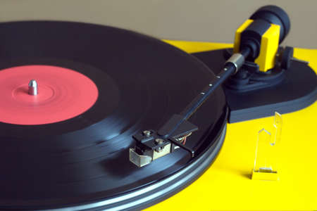 Playing vinyl LP record with red label on turntable with yellow case. Horizontal photo closeupの写真素材