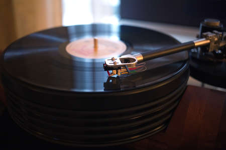 Vintage turntable rotating LP record in a room with subdued light. Horizontal view closeupの写真素材