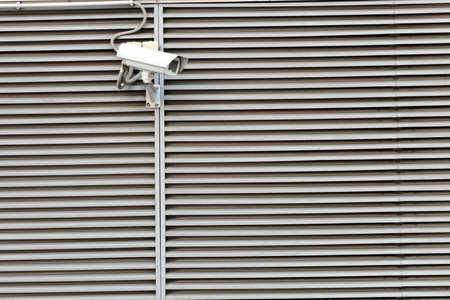 Security cam on modern city building stripe wall with long shadow in sunny dayの写真素材