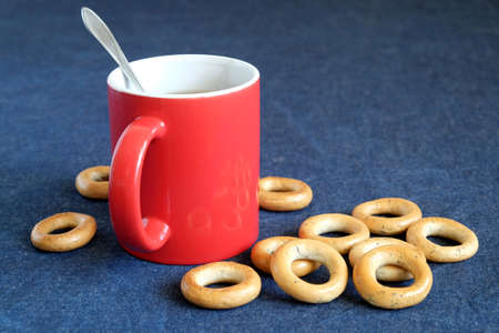 Red mug of black tea and dryings are on the table, covered with a blue cloth. Horizontal photo closeupの写真素材