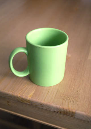 Empty green tea or coffee cup from ceramics on brown wooden kitchen table. Vertical photo closeupの写真素材