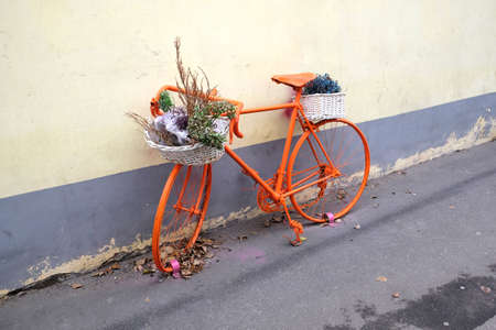 Retro style sport bike color orange with flower baskets as decoration outdoor near the wall side viewの写真素材