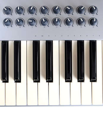 Fragment of electronic synthesizer keyboard with many control buttons isolated on white background top view closeupの写真素材