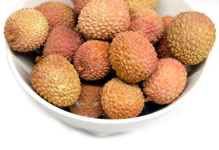 Many ripe lychee fruits isolated in white bowl top view closeupの写真素材