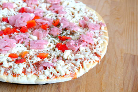 Still life with part of unready pizza on sandy brown wooden kitchen table top view closeupの写真素材