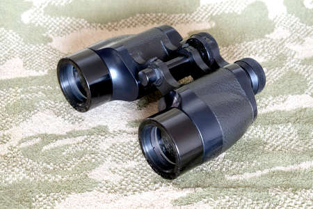 Vintage Porro prism black color military binoculars on camouflage background side view close upの写真素材