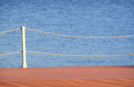 Brown wooden pier and blur, small waves on the sea surface after rope fenceの写真素材