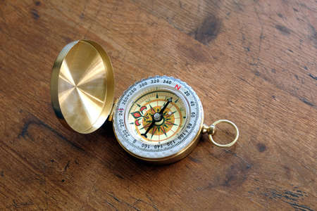 Old compass in opened brass case on vintage brown wooden backgroundの写真素材