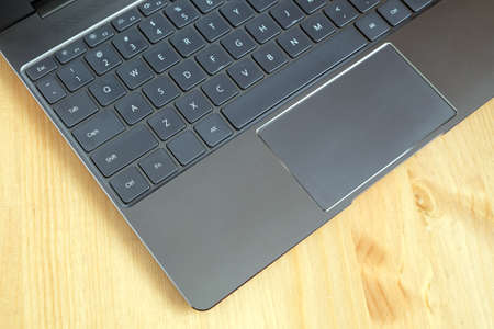 Part of opened laptop with keyboard, touchpad and empty mirror screen of black
