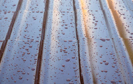 Fragment the wet brown metal roof of the house in the form of roof tiles with many drops after the rain, top view close upの写真素材