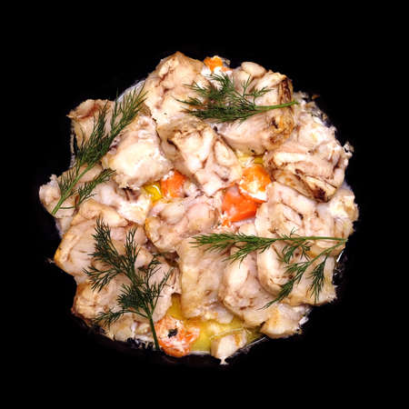 Fried white fish fillet with carrot and dill isolated on black
