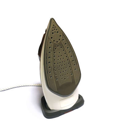 Modern electric iron with many steam holes on work surface stay in vertical position isolated on...