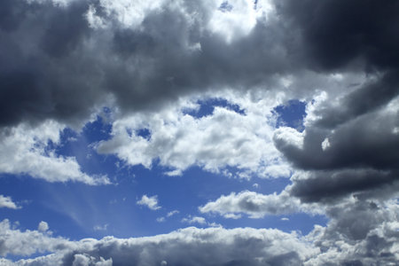 Beautiful heaven landscape with dense stormy white and gray clouds on different levels and some blue sky horizontal photoの写真素材